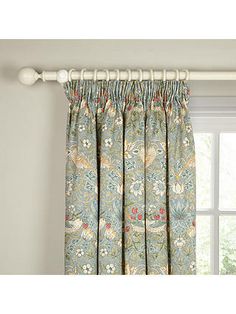 the curtain is hanging on the rod in front of the window with flowers and leaves