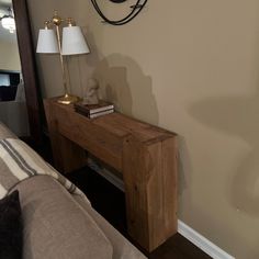 a wooden table sitting next to a lamp on top of a bed in a room