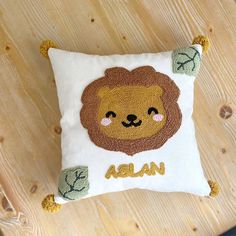 a pillow with a lion on it sitting on top of a wooden table next to a clock