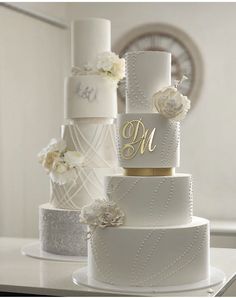 three tiered wedding cake with white flowers and monogrammed initials on each layer