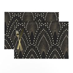 two placemats with gold forks and black art deco design, one on each side