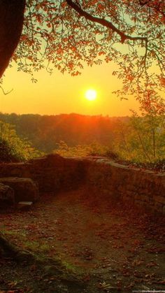 the sun is setting behind a stone wall