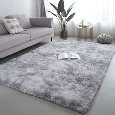 a living room with a gray couch and white rug on the floor in front of a window