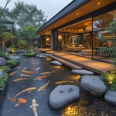 a house that has some rocks in the water and koi fish swimming around it