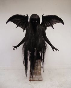 a creepy doll with long black hair and wings on it's head sitting in a vase