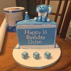 a blue and white birthday cake with an elephant on it's top sitting on a table