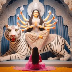 a woman sitting on top of a white tiger next to a statue of a woman