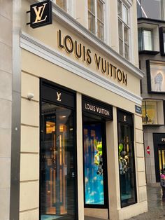 louis vuitton store front with people walking in the street behind it on a rainy day