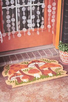 a door mat on the front step of a house that has been decorated with flowers and leaves