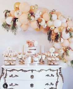 a table topped with lots of cake and desserts next to a bunch of balloons