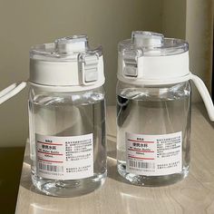 two glass jars sitting on top of a wooden table next to a white plastic object