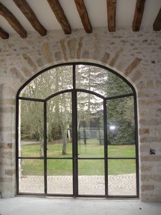 an open window in a stone building with grass and trees seen from inside the room