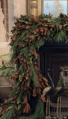 a fireplace decorated with greenery and fake birds in front of the fire mantel