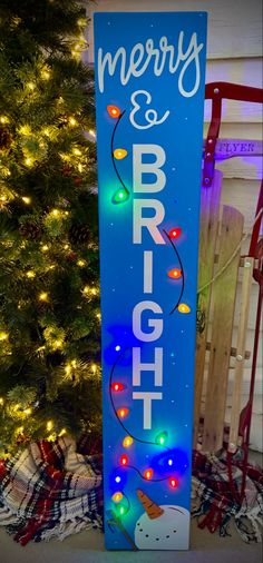 a blue sign that says merry and bright with lights on it next to a christmas tree