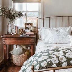 a bed sitting next to a wooden table with a basket on it's headboard