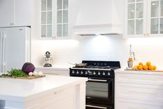 a kitchen with white cabinets and an island in the middle is shown, along with fruits and vegetables on the counter