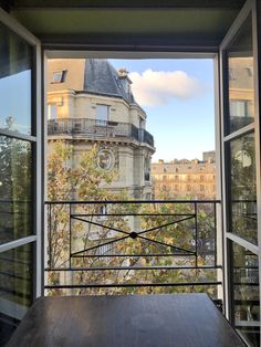 an open window with a view of the city and buildings from it's balcony