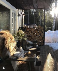 the back porch is covered in snow and logs