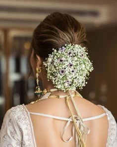 the back of a woman's head with flowers in her hair, wearing a white dress