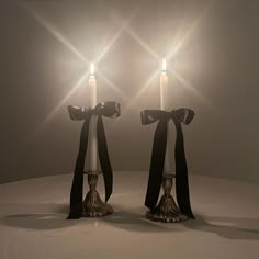 two white candles with black ribbons on them