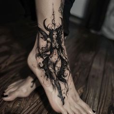 a woman's foot with a black and white tattoo design on her left leg