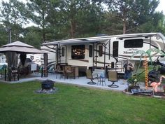 an rv is parked in the yard with tables and chairs