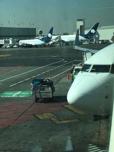 an airport tarmac with several planes parked on it and luggage being loaded onto the plane