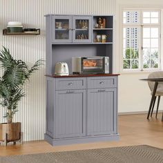 a kitchen with a gray hutch next to a potted plant