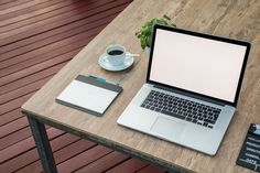 an open laptop computer sitting on top of a wooden table next to a cup of coffee