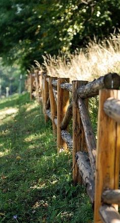 a wooden fence in the grass next to trees