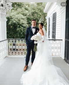 a bride and groom pose for a photo on the front porch of their wedding venue