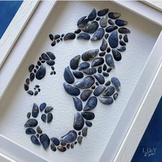 a seahorse made out of rocks in a white frame