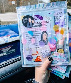 a person holding up a magazine in their hand with other items on the car dashboard