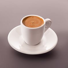 a cup of coffee sitting on top of a white saucer