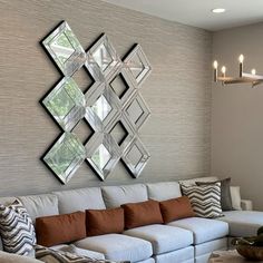 a living room filled with furniture and mirrors on the wall above it's couches