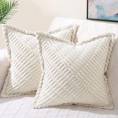 two white pillows sitting on top of a couch