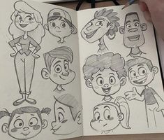 an open book with cartoon faces drawn on it's pages, and a person holding a pencil in their hand