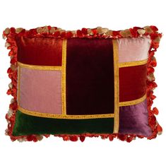 a red, pink and green pillow with pom - poms on the edges