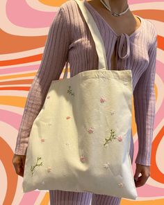 a woman holding a white bag with flowers on it