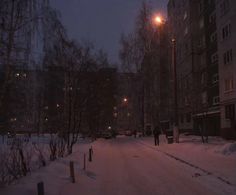 a snowy street at night with buildings and trees