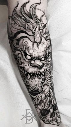 a black and white photo of a dragon tattoo on the arm, with clouds in the background