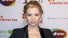 a woman in a black suit and pink lipstick on the red carpet at an awards event