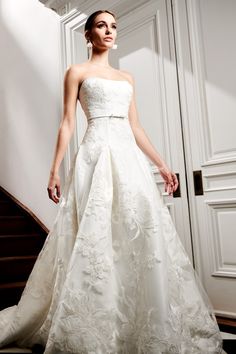 a woman in a white wedding dress standing next to a stair case with her hand on her hip