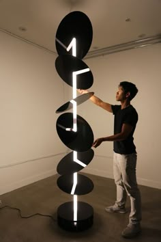 a man standing next to a tall black sculpture with white letters on it's sides