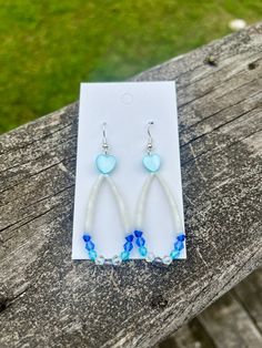 a pair of blue and white earrings sitting on top of a piece of paper next to a wooden bench