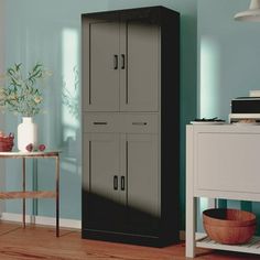 a tall black cabinet sitting in the corner of a room next to a white table