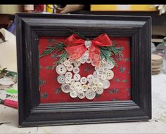 a red and black frame with buttons in the shape of a christmas wreath on it