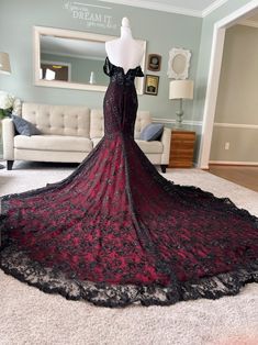 a black and red dress on display in front of a white couch with a mirror behind it