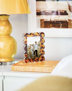 a yellow lamp sitting on top of a white table next to a book with an image of two people