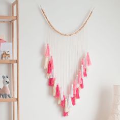 a wall hanging with pink and white tassels in a child's room